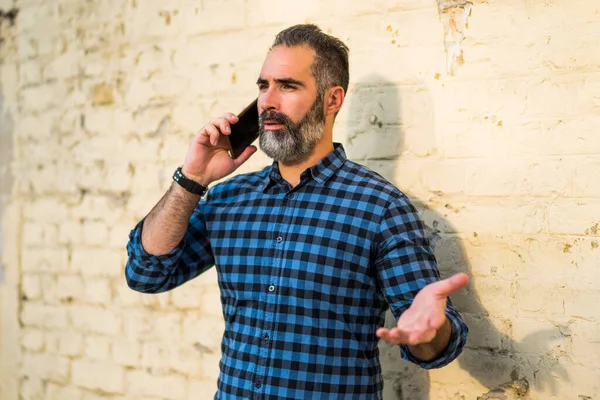 髭を生やしたビジネスマンが電話で誰かと話をしながら — ストック写真