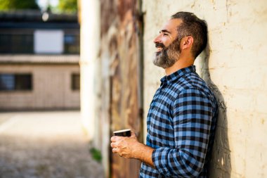 Sakallı bir iş adamı dışarıda kahve içmekten hoşlanır..