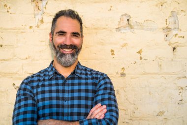 Tuğla duvarın önünde duran sakallı modern iş adamı portresi..