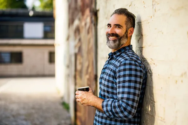 髭を生やしたビジネスマンが屋外でコーヒーを飲むのを楽しむ — ストック写真