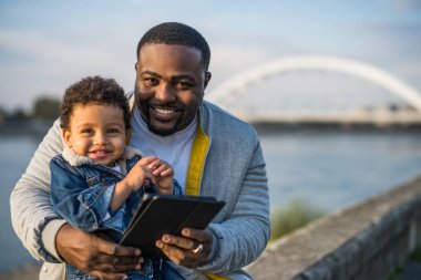 Baba ve oğlu dışarıda otururken dijital tablet kullanıyorlar..