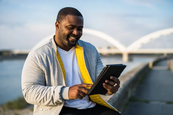 Moderner Schwarzer Mann Nutzt Digitales Tablet Während Fluss Sitzt — Stockfoto