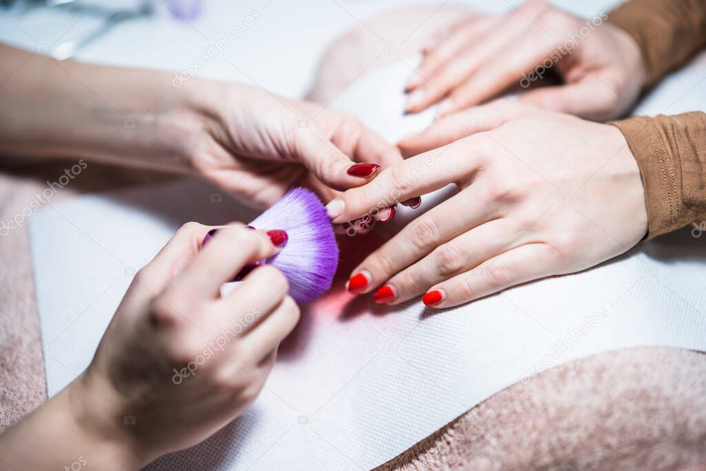 Close up image of manicure process, manicurist cleaning fingernail  after removing old  gel varnish. Focus on fingernail.