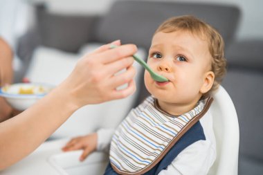 Sandalyede otururken yemek yiyen tatlı bir oğlan..