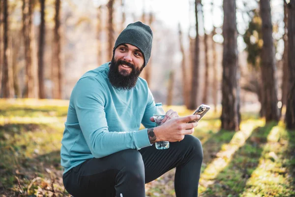 Uomo Che Utilizza Telefono Acqua Potabile Dopo Esercizio Nella Natura — Foto Stock