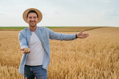 Mutlu çiftçi buğday tarlasını gösteriyor..