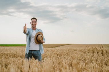 Mutlu çiftçi buğday tarlasında dikilirken kendini gösteriyor..