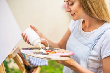 Woman enjoys painting on canvas outdoor.