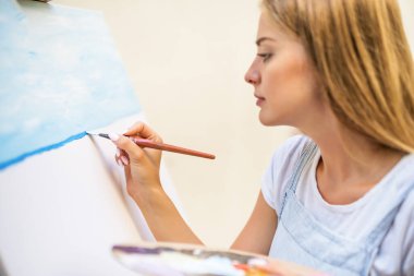Woman enjoys painting on canvas outdoor.