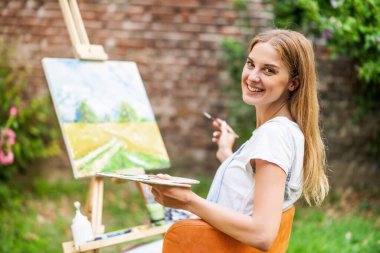 Woman enjoys painting on canvas outdoor.