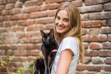 Woman and  her beautiful black cat  enjoy spending time together outdoor.