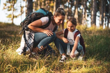 Anne ve kızı yürüyüş yaparken cam büyüteçle etrafı keşfediyorlar..