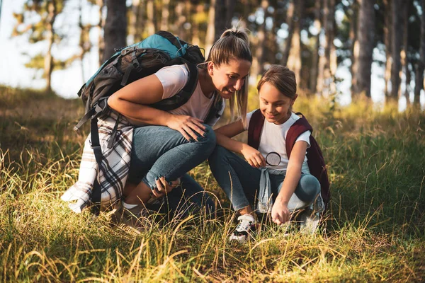 Anne ve kızı yürüyüş yaparken cam büyüteçle etrafı keşfediyorlar..