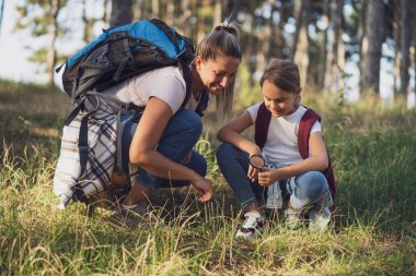 Anne ve kızı yürüyüş yaparken cam büyüteçle etrafı keşfediyorlar..