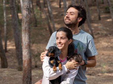 Mutlu genç beyaz çift sonbaharda ormanda Minyatür Dachshund köpekleri ile gülümsüyor.