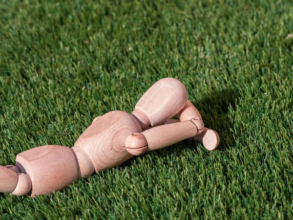 İnsan ahşap bebek çimenlerin üzerinde uzanmış, güneşleniyor.