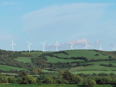 Rüzgâr santrallerinin dağdaki mavi gökyüzü ve elektrik üretimi için güneşli tarlalara kurulumu