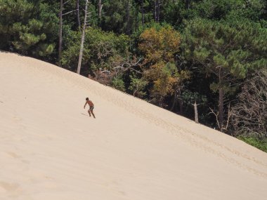 Young caucasian man walking and jumping on the sand in Dune of Pilat in Arcachon France