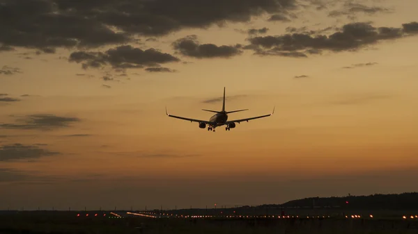 Avión aterrizando en una puesta de sol — Foto de Stock