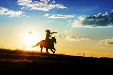 Cowgirl silhouette riding off into sunset clipart