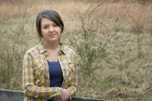Country girl in flannel shirt by fence — Stock Photo, Image