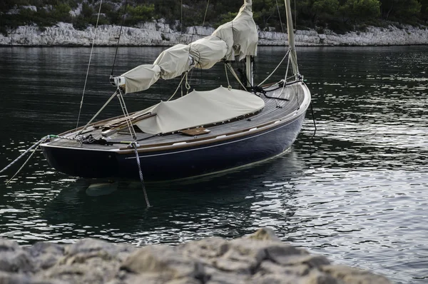 Sailing boat anchoring with landlines moored to shore — Stock Photo, Image