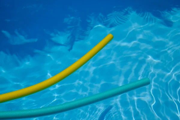 Macarrão amarelo e azul na piscina. água azul . — Fotografia de Stock