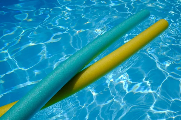 Fideos amarillos y azules en la piscina. agua azul . — Foto de Stock