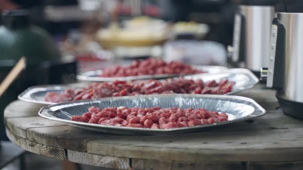 Alumínium fólia tartályok különböző húselőételekkel az Oktoberfest vendégei számára készített fa asztalon, fűszeres szalámi szeletek piknik party ünneplésére. Étvágyfokozók és rágcsálnivalók a bbq partira — Stock videók