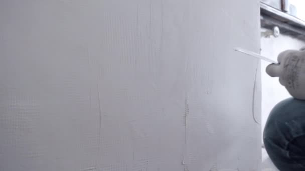Reparateur in Arbeitskleidung klebt rekonstruierte Zementwand unter dem Fenster mit Metallkelle, Spachtel und weißer Spachtelmasse, Mann nivelliert Wandoberfläche mit Spachtel-Stuck. Mauersanierung — Stockvideo