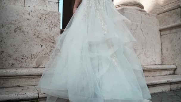 Beyaz dantelli gelinlikli güzel bir kadın Capitoline Hill 'de yavaşça yürüyor mermer merdivenlerden tırmanıyor, uzun dantelli duvak düğün sonrası düğün yürüyüşü sırasında yere uzanıyor. — Stok video