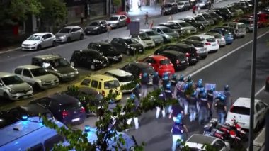 ROME, ITALY - 6 Temmuz 2021: Zırhlı İtalyan polis memurları gece sokak protestocularına saldırdı, üç polis arabası yavaş yavaş polis taktik birimini bastırmak için acil durum sireniyle yanıp sönüyor