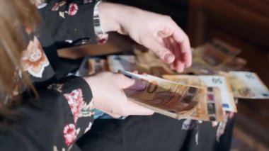 Kadın evde piyango parası ödülünü sayıyor ve yere avro banknotları atıyor. Avro kâğıt para destesini tutan ve nakit para sayan kişi. Kadın milyoner kontrol ediyor.