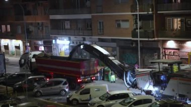 ROME, ITALY - 9 Nisan 2021: not makinesi ve çöp kamyonu gece yolda çalışıyor, not öğütücü yol çizgisi, asfalt sıkma ve kamyona atma. Gece yolu inşaatta çalışır.