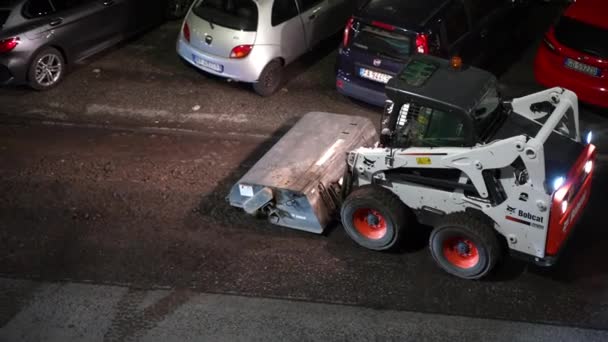 ROMA, ITALIA - 9 DE ABRIL DE 2021: Camión grader blanco que retira restos de asfalto molido durante el tráfico nocturno en las calles de Roma, trabajador del equipo que conduce a lo largo de la carretera y limpia parte de la carretera molida — Vídeos de Stock