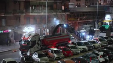 ROME, ITALY - 9 Nisan 2021: Roma caddesinde yol çalışmaları, takım çalışanları yıkık asfaltı not makinesiyle temizliyor ve çöp kamyonuna asfalt tozu atıyorlar. Yolda tamir işleri.