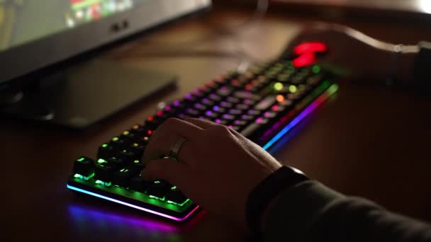 Teclado moderno com iluminação retroiluminada RGB, conceito de espectro de néon. Close-up de dedos humanos clicando no teclado colorido e mouse, especialista em computadores jogando jogos de vídeo online em casa — Vídeo de Stock