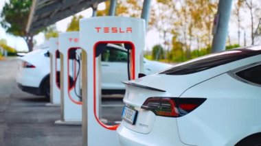 Otomatik elektrik Tesla arabası süperşarj istasyonunda şarj enerjisini dolduruyor 
