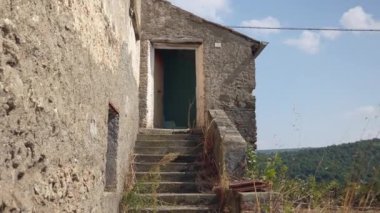 İtalya 'nın dağlık bölgelerindeki harabe kırsal yerleşim yerleri, yeşil merdivenler, kırık kapılar ve pencerelerle kaplı eski yıkık evler, harap olmuş dış cephe kaplamaları. Boş hİtalyanca
