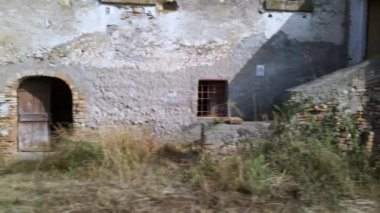 Dağlarda terk edilmiş geleneksel İtalyan köyü, yol kenarındaki eski harabe çiftlik evi. Kırık camları, paslı ızgaraları ve kapıları olan terk edilmiş bir ahır. Çiftlik için kullanılan antik sanayi evleri
