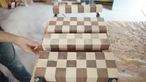 Proceso de encolado de madera en planta de producción, carpintero aplicando pegamento para sujetar barras de madera en tablero sólido. Artesano trabajando en taller, trabajo hecho a mano en la industria manufacturera — Vídeo de stock