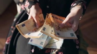 Tanımlanamayan bir kadın elinde 20 ve 50 avroluk banknotlar tutuyor ve onları sayıyor, namussuz kadın iş ortağı evde kirli parayı hesaplıyor. Rüşvetçi, yasadışı mali ellerde Euro parası