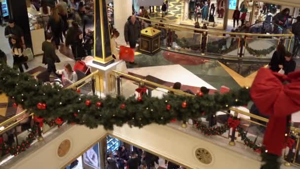 ROMA, ITÁLIA - 19 DE DEZEMBRO DE 2019: Shopping center lotado lindamente decorado com galhos de árvores de Natal, guirlandas brilhantes, fitas vermelhas e bolas, vista superior de pessoas andando dentro das compras — Vídeo de Stock