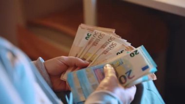 Başarılı milyonerlerin elinde Euro banknotları, evdeki piyango ödülünü sayan bir kadın. Avro parası, piyango bütçesi ve kolay para konsepti.