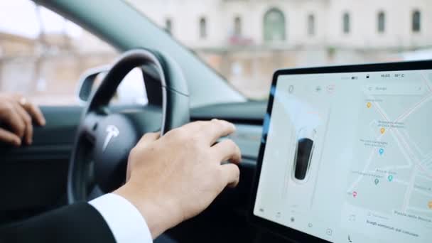 ROME, ITALY APRIL 28, 2021: Seorang pria dalam setelan bisnis memegang test drive dari mobil otonom Tesla Model 3 berteknologi tinggi, pengemudi menyalakan dan mematikan fungsi pada roda kemudi yang terhubung dengan — Stok Video