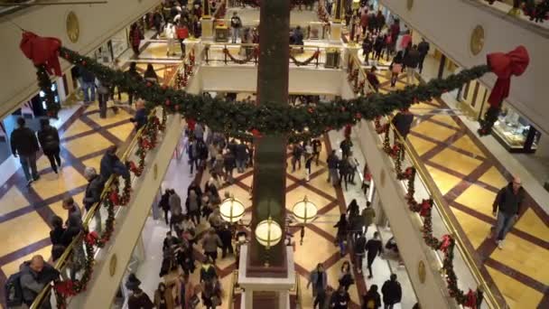 ローマ,イタリア- 2019年12月19日:クリスマスツリーの枝、輝くガーランド、赤いボールとリボンで飾られた有名なローマのショッピングセンター、フロア、店舗での休日前の喧騒 — ストック動画