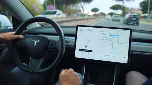 ROME, ITALY - APRIL 28, 2021: Man driving on autopilot in innovative electric Tesla car, driver holding steering wheel, setting self-driving function on LCD touchscreen monitor and driving with no — Stock Video