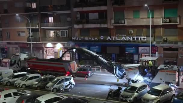 ROMA, ITALIA - 9 DE ABRIL DE 2021: Trabajos nocturnos de reparación de carreteras con maquinaria pesada de nivelación y camión volquete, asfalto molido tirando al camión después de retirarlo. Preparación de la línea de carreteras para pavimentar nuevos — Vídeo de stock