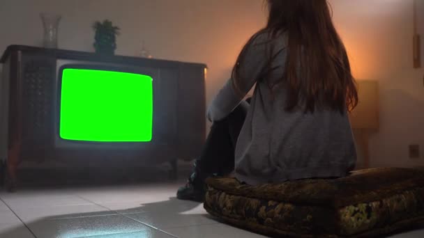 Vista posterior de la mujer sentada en la almohada en el suelo y viendo retro TV con pantalla verde parpadeante monitor, persona sola estar sola en casa sentada frente a la vieja televisión con directo — Vídeos de Stock