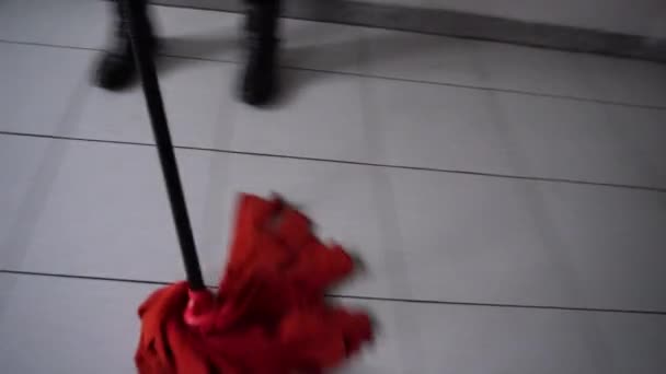 Kamera bewegt sich mit der Bewegung des roten Nasswischers auf dem Boden, unkenntliche Frau reinigt Boden mit Flüssigwaschmittel und Nasswischmittel. Konzept der Hygiene und Sauberkeit — Stockvideo